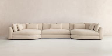 A large, U-shaped modular sectional sofa upholstered in light beige fabric, featuring various straight and curved sections, loose back cushions, and wide track arms, designed for extensive seating. — 3D model