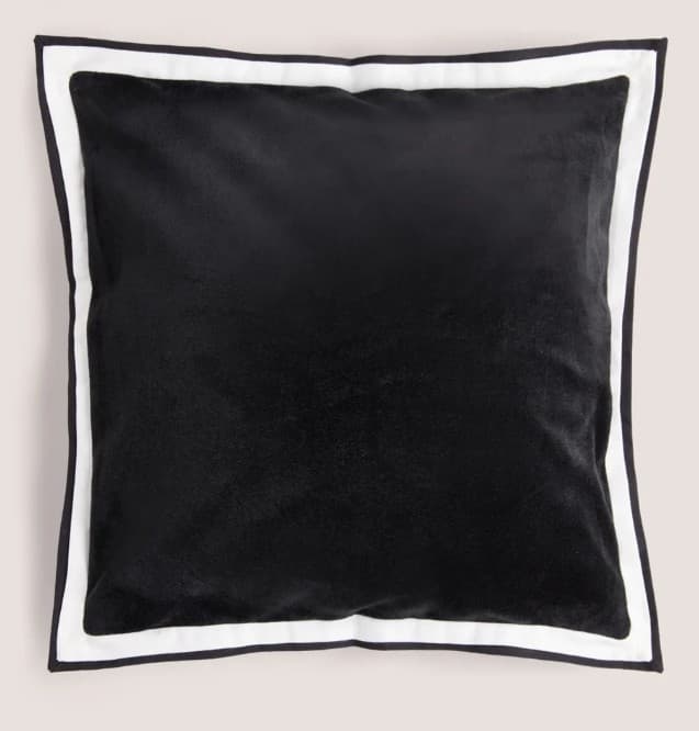 A square cushion with a plush black surface and a contrasting white and black trim around its edges. The trim appears to be piped, with a thin black line bordering a wider white band, which in turn is bordered by another thin black line. The black surface has a soft, velvety texture. — 3D model
