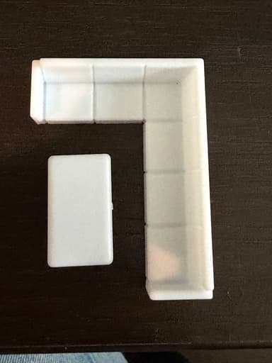 A miniature, simplified model of an L-shaped modular sectional sofa in white, paired with a matching rectangular coffee table, depicted against a white background. — 3D model