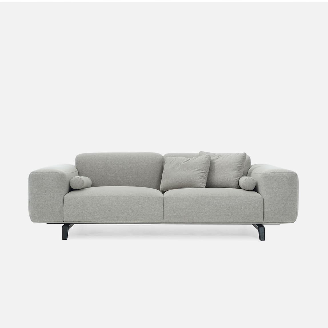 A modern upholstered sofa in a light grey fabric, featuring two main seat and back cushions, with integrated wide armrests and two bolster cushions. The sofa is supported by dark, minimalist metal legs. — 3D model