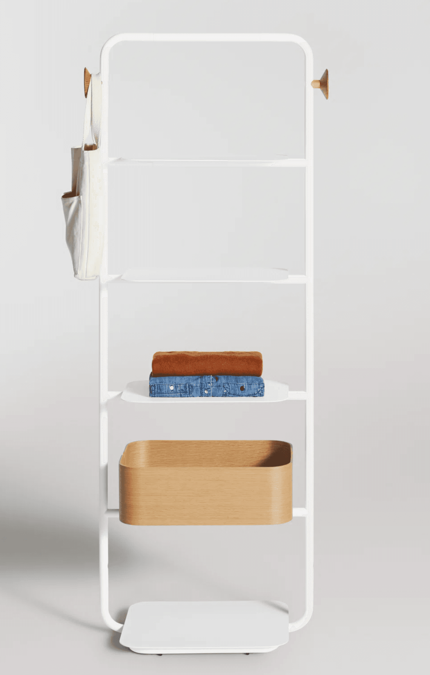 A tall, slender wall-mounted shelving unit featuring a white metal frame, multiple white metal shelves, and one integrated light wood storage basket. The frame has rounded corners, and there are two small wooden knobs at the top. — 3D model