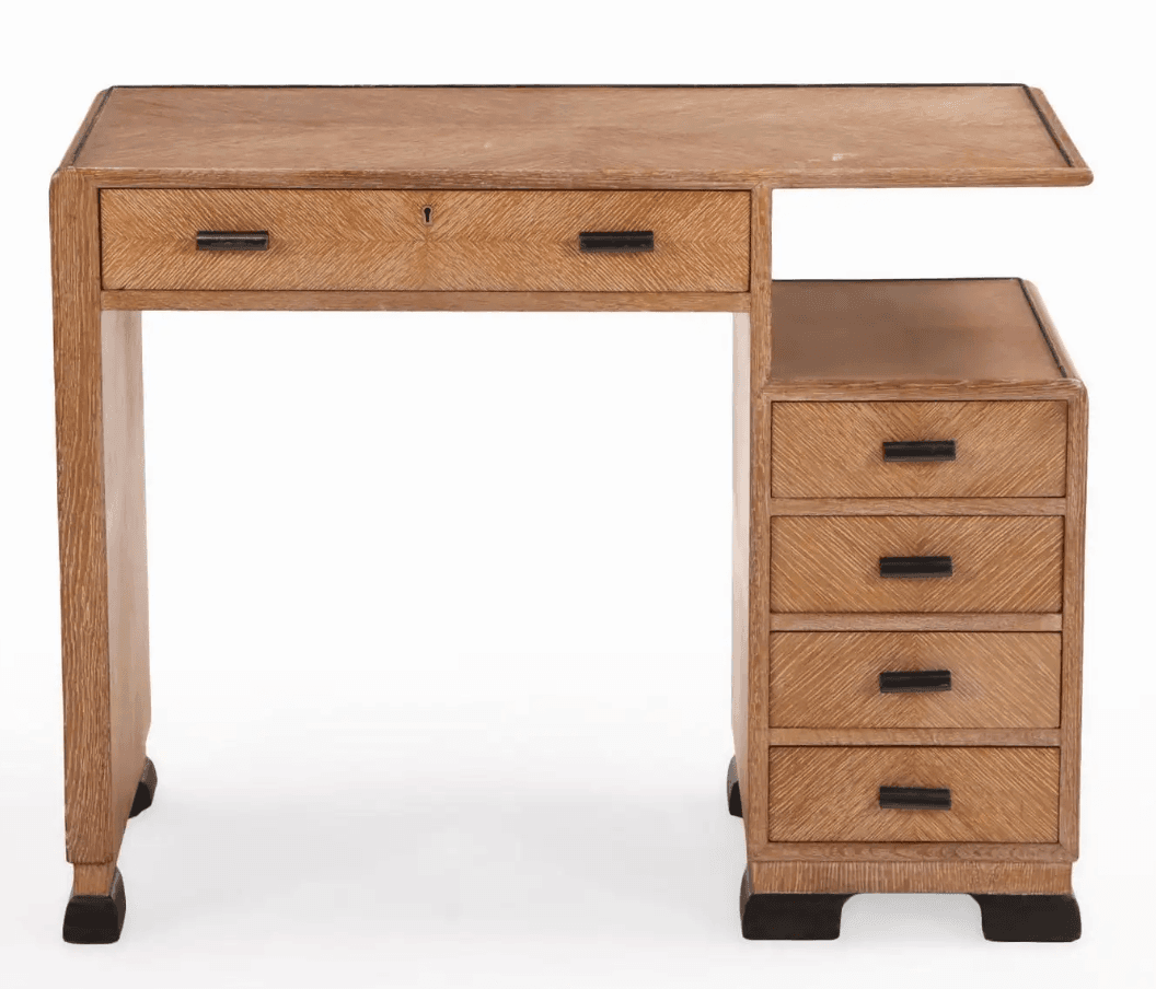 A wooden desk featuring a parquet veneer finish on its drawers and table surface. It has a cantilevered section extending from the main tabletop. The desk includes one wide drawer with a keyhole and two dark-toned handles, positioned above a leg. To the right, a vertical unit comprises four drawers, each with a dark-toned handle. The desk is supported by two legs and rests on dark, geometric feet. — 3D model