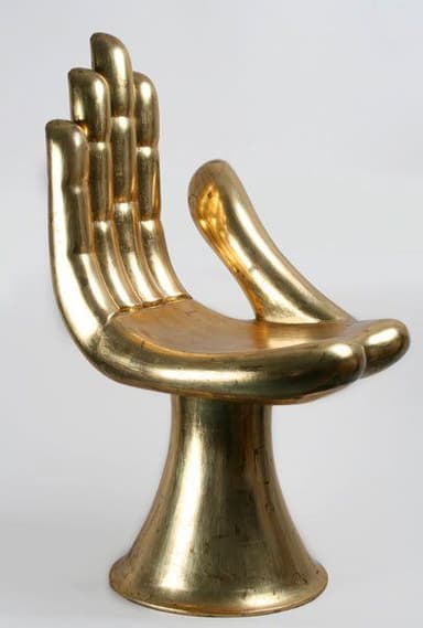 A striking gold-colored chair designed in the sculptural form of an open human hand, featuring fingers as a backrest and the palm as the seat, supported by a flared pedestal base. — 3D model