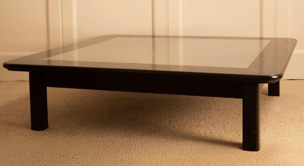 A low-profile square coffee table with a dark-finished wooden frame and a recessed, lighter-colored central panel on its top. It stands on four stout, straight legs. — 3D model