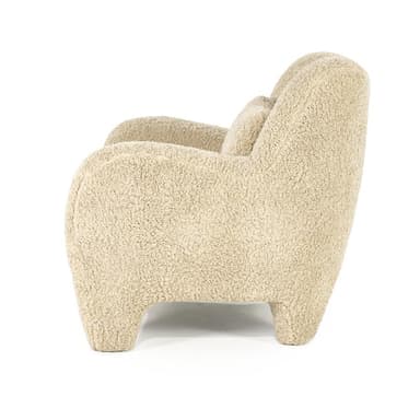 A cream-colored armchair with a rounded silhouette, upholstered in a textured fabric resembling boucle or sherpa. It features broad, enveloping arms, a high back, and four short, chunky legs. A small, square throw pillow with matching upholstery is placed on the seat against the back. — 3D model