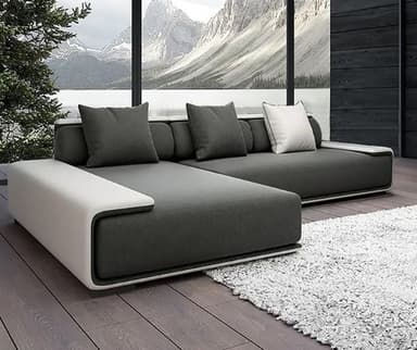 An L-shaped modern sectional sofa featuring dark gray fabric upholstery and a contrasting light-colored frame that forms integrated console arms and back support. The sofa has a low profile, comprising a main seating section and a chaise lounge component. It includes several square throw pillows, some matching the dark gray upholstery and one in white with dark piping. — 3D model