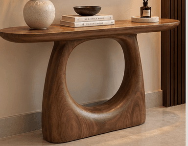 An organic modern console table crafted from dark walnut wood, featuring a smooth, oblong tabletop and a distinctive sculptural base with a curvilinear, open form. The entire piece appears to be seamlessly constructed, showcasing the natural grain of the wood. — 3D model