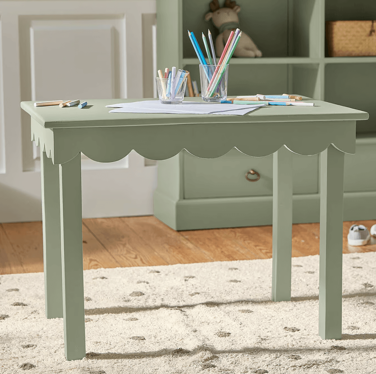 A small, rectangular dining table with a scalloped apron beneath the tabletop and four straight legs. The table is painted a solid, muted green color. — 3D model