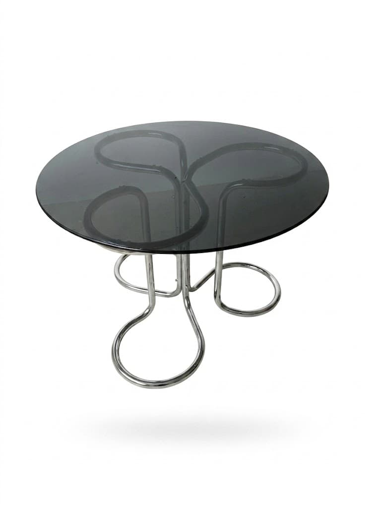 A circular coffee table with a smoked glass top and a chrome-plated metal base. The base features an abstract, sculptural design with curved tubes forming a tripod-like structure. — 3D model