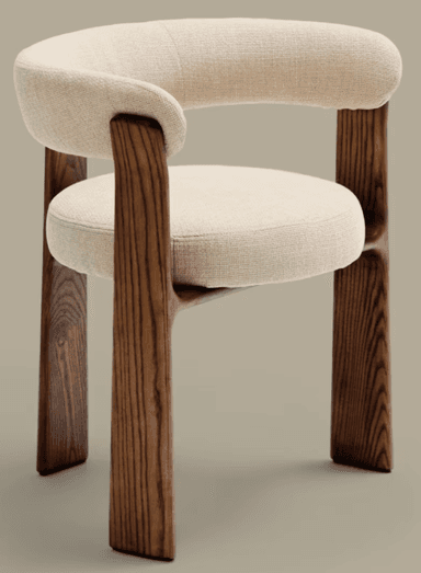 A modern armchair with a curved upholstered backrest and seat, supported by four solid wood legs. The legs have a distinct organic shape and visible wood grain. The upholstery is a textured, light-colored fabric. The design is minimalist and contemporary. — 3D model