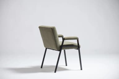 An armchair with a dark-colored frame and upholstered seat, back, and armrests in a light olive green fabric. The frame appears to be made of metal or a dark wood, with slender legs and arm supports. The upholstery has a textured weave. The design suggests a mid-century modern or contemporary aesthetic. — 3D model