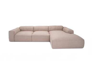A sectional sofa with a chaise lounge extension. The sofa features a low profile, clean lines, and deep, plush seating. It is upholstered in a textured, neutral-toned fabric. The design appears modular or composed of distinct sections. — 3D model