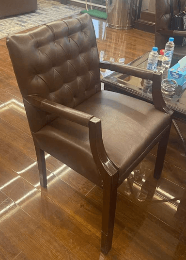 A traditional executive armchair upholstered in rich brown leather, featuring a deeply button-tufted backrest and solid wooden armrests and legs. — 3D model