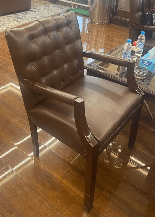 A traditional executive armchair upholstered in rich brown leather, featuring a deeply button-tufted backrest and solid wooden armrests and legs. — 3D model