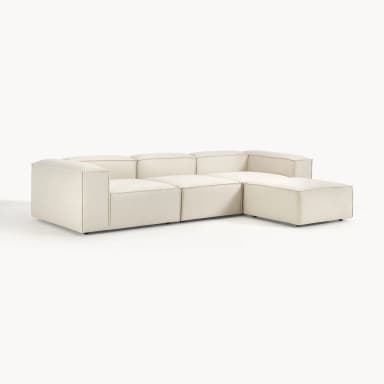 A cream-colored, modern modular sectional sofa, configured in an L-shape with a chaise lounge extension. The design features low-profile arms and backrests, with visible piping or top-stitching along all edges, indicating its modular construction with separate, upholstered blocks. — 3D model