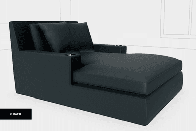 A contemporary, sleek black faux leather chaise lounge featuring a low backrest, broad fixed armrests with integrated metal cupholders, and two matching throw pillows. — 3D model
