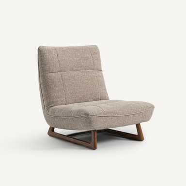 A modern armchair with a low profile and a sloped backrest. The armchair features upholstered seating and back cushions with subtle tufting. It is supported by a minimalist wooden base with angled legs. — 3D model