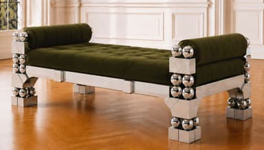 A striking postmodern daybed featuring a polished chrome frame with intricate geometric and spherical details, paired with a tufted, rich brown upholstered cushion and cylindrical bolster pillows at each end. The metallic frame consists of rectangular and triangular elements adorned with stacked chrome spheres, creating a bold and reflective aesthetic. — 3D model