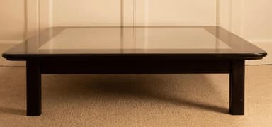 A low-profile square coffee table with a dark-finished wooden frame and a recessed, lighter-colored central panel on its top. It stands on four stout, straight legs. — 3D model