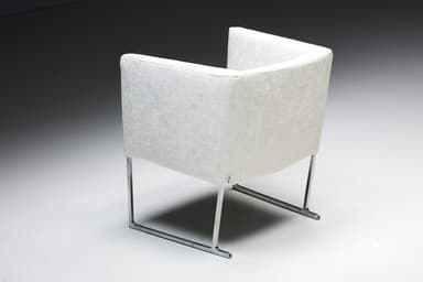 A set of four identical armchairs with a modern design. Each armchair features a cube-like upholstered seat and backrest with squared arms. The upholstery appears to be a textured fabric. The chairs are supported by a sleek, minimalist frame, likely made of polished metal, elevating them slightly off the ground. The overall aesthetic suggests a contemporary or minimalist style. — 3D model