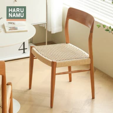 An armless dining chair constructed from light-toned natural wood, featuring a curved backrest and a square seat upholstered with woven rattan. The chair has a minimalist design with a visible wood grain and simple, sturdy legs. — 3D model