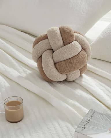 A decorative cushion featuring a complex, spherical knot design made from two intertwined tubular fabric elements, one beige and one brown, showcasing a soft, textured finish. — 3D model