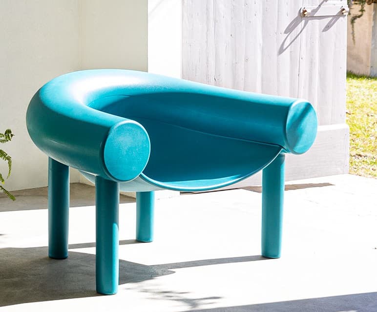 A modern, minimalist lounge chair in a vibrant teal color, featuring a U-shaped backrest and integrated armrests, supported by four cylindrical legs. The design is seamless and sculptural. — 3D model