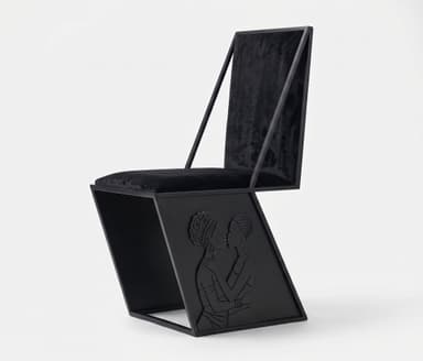 An avant-garde chair featuring a striking geometric, Z-shaped frame constructed from black metal. The seat and backrest are upholstered in plush black velvet, providing a stark textural contrast to the rigid frame. The lower portion of the chair's side incorporates a rectangular panel with an embossed relief depicting two figures in an embrace, rendered in the same matte black finish as the frame, adding a distinct artistic and narrative element. — 3D model