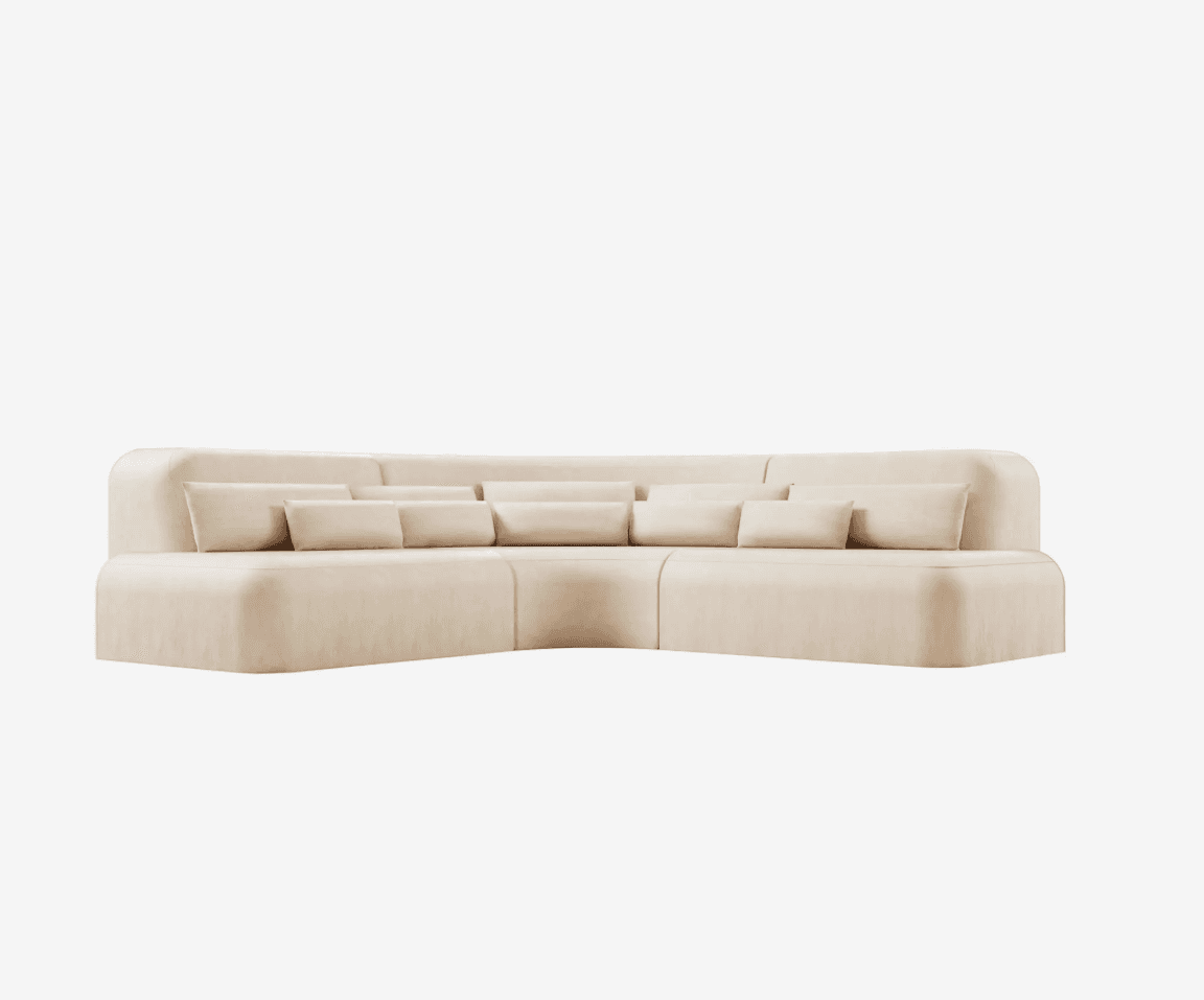 A sectional sofa with a curved form, upholstered in a light cream fabric. It features a low profile and rounded armrests. The seat and back cushions are plush, and several matching throw pillows are placed along the back. — 3D model