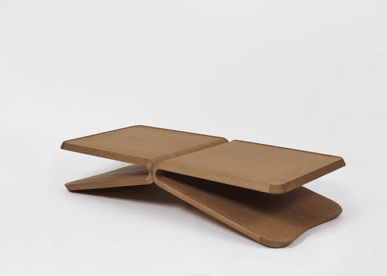 A low-profile, two-tiered coffee table crafted from light-toned wood, featuring an organic, sculptural design. The two flat, rectangular surfaces with softly rounded corners are connected by a continuous, gracefully curved central element, creating a seamless and minimalist form. — 3D model