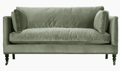 A contemporary two-seater sofa featuring a clean-lined silhouette, track arms, and plush cushioning. Upholstered in a soft, light green velvet or similar fabric, it includes two loose back cushions and a single bench-style seat cushion. The base is adorned with decorative nailhead trim along the bottom edge, and it stands on dark turned wood legs, with the front legs equipped with metal casters. — 3D model
