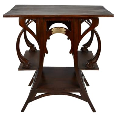 A dark wooden accent table with a rectangular top and two lower shelves. The table features ornate, curved wooden supports that create an open, sculptural base. A small, decorative brass plaque is affixed to one of the central supports. — 3D model