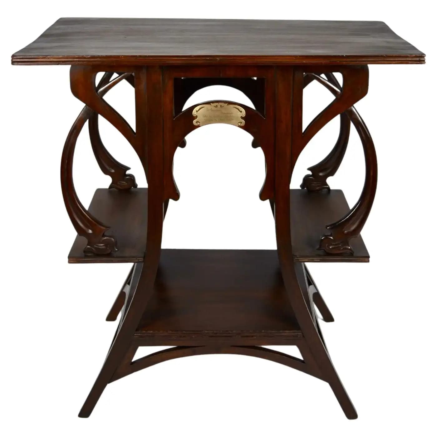 A dark wooden accent table with a rectangular top and two lower shelves. The table features ornate, curved wooden supports that create an open, sculptural base. A small, decorative brass plaque is affixed to one of the central supports. — 3D model
