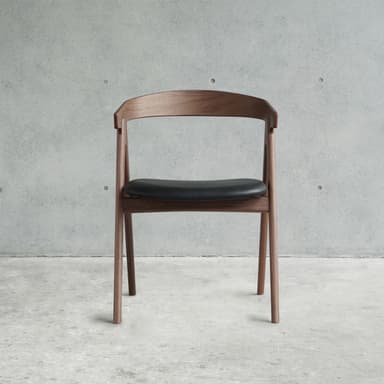 A modern dining armchair constructed from dark walnut wood, featuring a gracefully curved backrest that seamlessly transitions into integrated armrests. The seat is upholstered in a black material, likely leather or leatherette, with a subtle contour for comfort. The chair stands on four sturdy, tapered wooden legs, and the overall design suggests a blend of mid-century modern and Scandinavian aesthetics. — 3D model