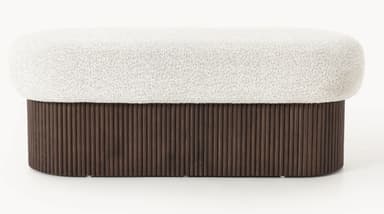An elongated, oval-shaped bench featuring a plush, textured cream boucle upholstered top set upon a solid, dark brown wood base with vertical reeding details. The design is contemporary, emphasizing both tactile comfort and a structured, organic aesthetic. — 3D model