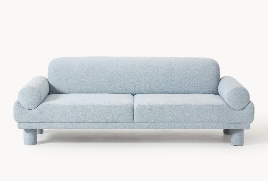 A light blue, plush-textured sofa with a rounded backrest and armrests. It features two seat cushions and four cylindrical legs. The overall design is modern and minimalist with soft, organic curves. — 3D model