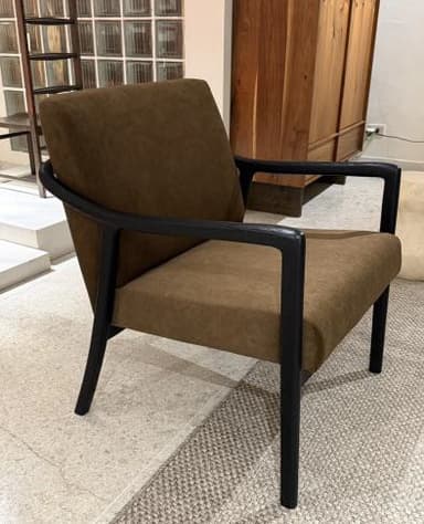A contemporary armchair with a upholstered seat, backrest, and armrests. The frame and legs are constructed from dark material, providing a contrasting visual element to the warm brown upholstery. The design is minimalist and modern. — 3D model