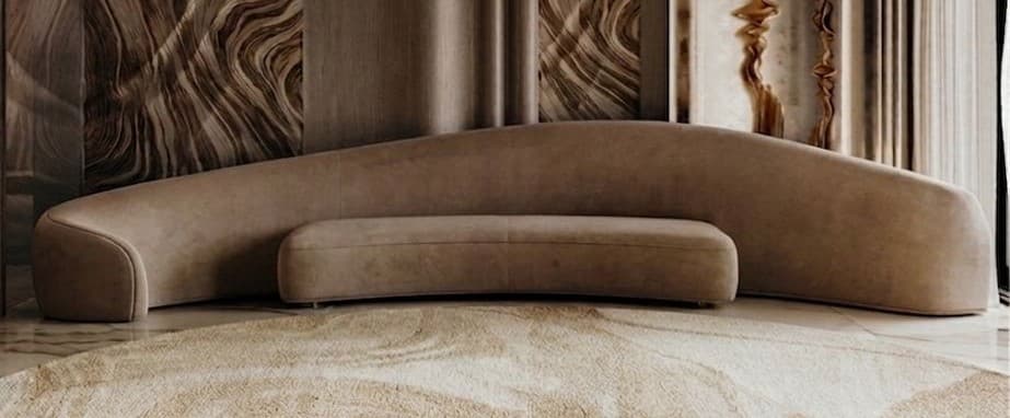 A modular, curved sofa with a rounded, organic form. It consists of two sections that form a gentle arc, with one section appearing lower and more akin to a bench or ottoman. The upholstery has a soft, matte texture. The overall design is modern and minimalist. — 3D model