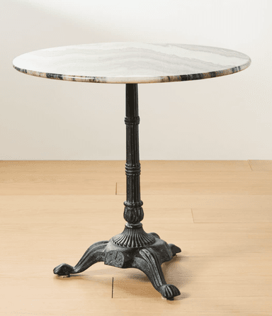 A round table featuring a polished white marble top with natural grey veining, supported by a dark, ornate cast iron pedestal base with decorative detailing and four splayed, paw-like feet. — 3D model