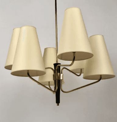 A vintage Mid-Century Modern chandelier featuring a central brass stem descending from a ceiling canopy. Six radiating arms, also in brass, extend outwards, each terminating in an upward-pointing, conical, off-white fabric shade. The central column has a prominent black accent piece, providing a striking contrast to the brass finish. The design is characteristic of the 1950s to 1960s, emphasizing clean lines and functional elegance. — 3D model
