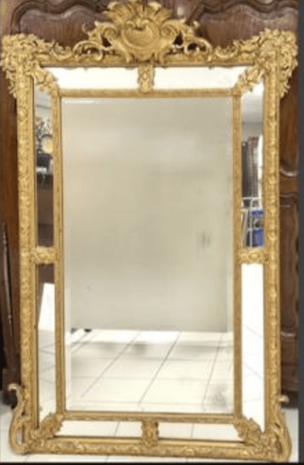 A rectangular mirror with an ornate, gilded frame. The frame features intricate carvings and decorative elements, including scrolling acanthus leaves and a cartouche at the top. The mirror surface appears to be glass. — 3D model