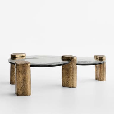 A contemporary coffee table with a circular, smoked glass top supported by four uniquely shaped, textured metallic legs. The legs appear to be cylindrical with irregular, rough surfaces and are finished in a bronze-like hue. The overall design is minimalist yet impactful, with the textured legs contrasting with the smooth glass. — 3D model