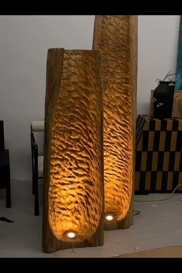A tall, cylindrical floor lamp crafted from a solid piece of wood, featuring a deeply carved interior surface that creates an organic, rippled texture. A spherical light source is recessed at the base of the carved cavity, emitting a warm glow that highlights the natural wood grain and intricate textures. The exterior of the lamp maintains a more natural, tree-trunk-like appearance. — 3D model