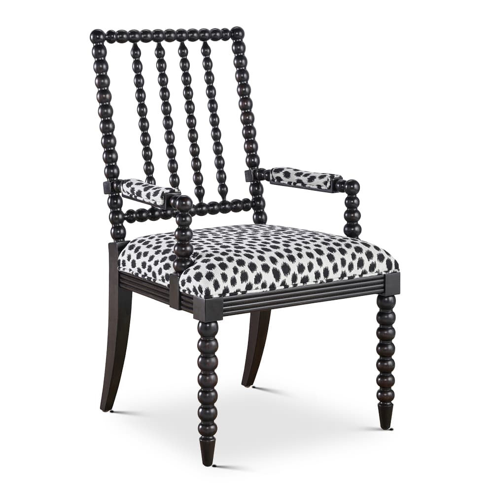 An armchair featuring a distinctive bobbin-turned frame crafted from dark-stained wood. The seat and armrests are upholstered in a bold black and white animal print fabric. The backrest consists of vertical bobbin spindles and a matching top rail, supported by four legs, with the front two showcasing the full bobbin design. — 3D model