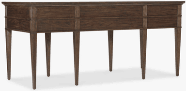 A dark brown wooden desk featuring a rectangular top, multiple drawers, and reeded tapered legs. The desk has a central knee space, flanked by two sections each containing two stacked drawers. Above the knee space, there is a single, shallower drawer. All drawers are fitted with square brass pulls featuring an etched geometric pattern. The reeded texture is present on the vertical elements of the frame and the tapered legs, adding a classical detail to the transitional design. — 3D model