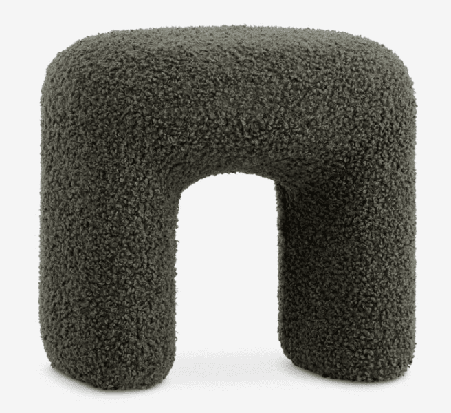 A contemporary U-shaped stool upholstered in a dark green boucle fabric. The stool features soft, rounded edges and a sculptural form, providing both a unique aesthetic and comfortable seating. Its entire surface is covered in the textured, looped yarn fabric. — 3D model