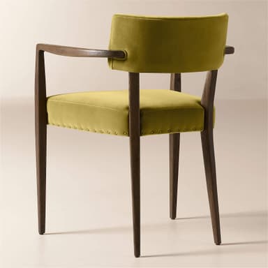 A wooden armchair with upholstered seat and back. The frame is constructed from dark wood with visible grain. The seat and back are upholstered in a textured, mustard-yellow velvet fabric. The upholstery on the seat is secured with a row of decorative brass tacks around its perimeter. The armrests are integrated into the wooden frame and extend from the backrest support to the front legs. — 3D model