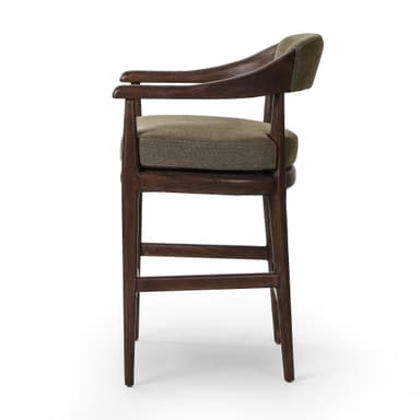 A bar stool with a wooden frame and upholstered seat and backrest. The frame is constructed from dark wood with visible grain. The seat and backrest are upholstered in a textured, olive-green fabric. The stool has a curved backrest that extends to armrests, and its legs are supported by crossbars. — 3D model