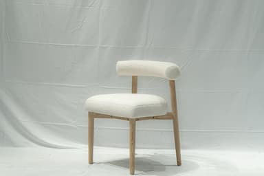 A contemporary side chair with a rounded backrest and seat upholstered in a textured, boucle fabric. The chair features a light-colored wooden frame with four tapered legs. The design is minimalist and modern. — 3D model