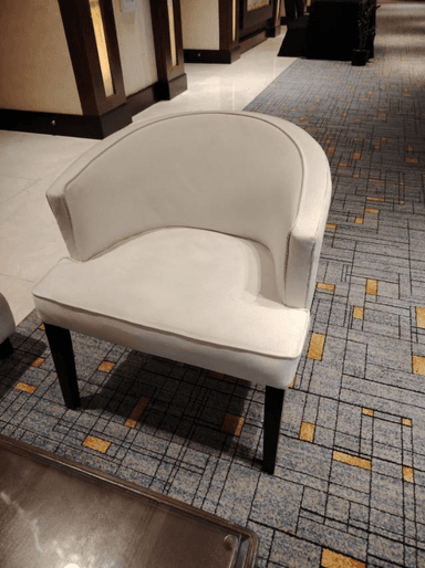 An off-white upholstered tub-style armchair with dark tapered legs and light grey contrasting piping. — 3D model
